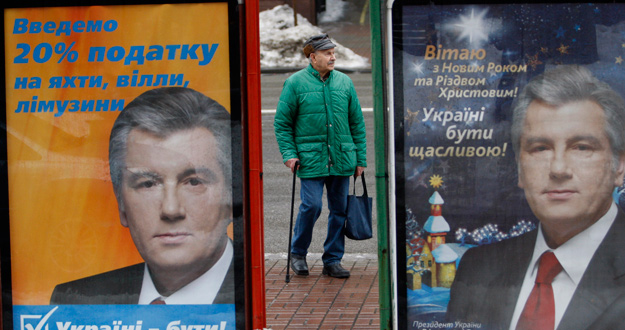 Un hombre en una parada de autobús de Kiev entre carteles del presidente Yushchenko.