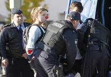 A woman wearing a clown's nose is detained by police during a protest against the NATO summit in Lisbon