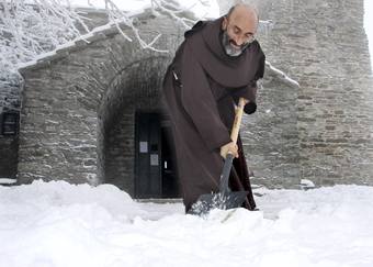 El fraile franciscano José que llego a la capilla do Cebreiro el pasado mes de octubre, retira la nieve de la entrada esta mañana, tras la intensa nevada de la pasada noche.