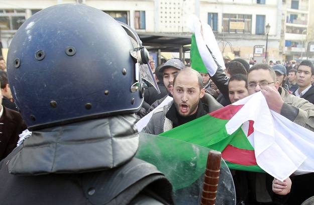 Protesters chant slogans in front of a policeman during a demonstration in Algiers