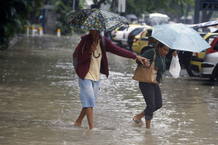 Dos mujeres se protegen de la lluvia en medio de las inundaciones en Río.