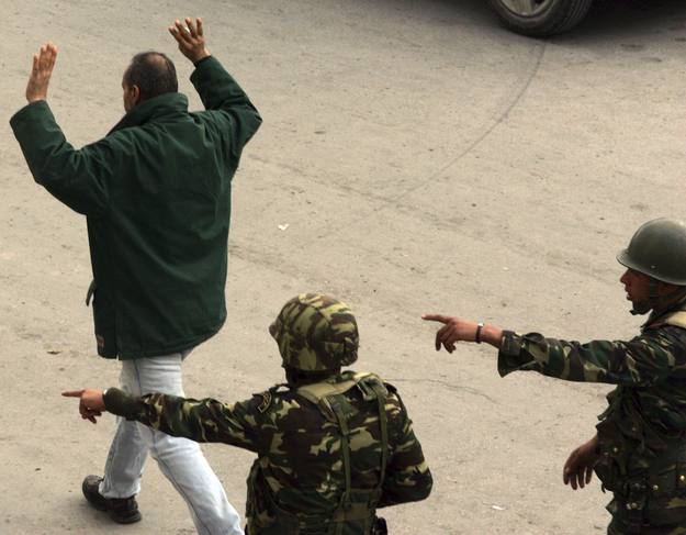 Un hombre pasa con las manos en alto delante de unos soldados tunecinos mientras centenares de personas se manifiestan frenta al Ministerio del Interior de Túnez.