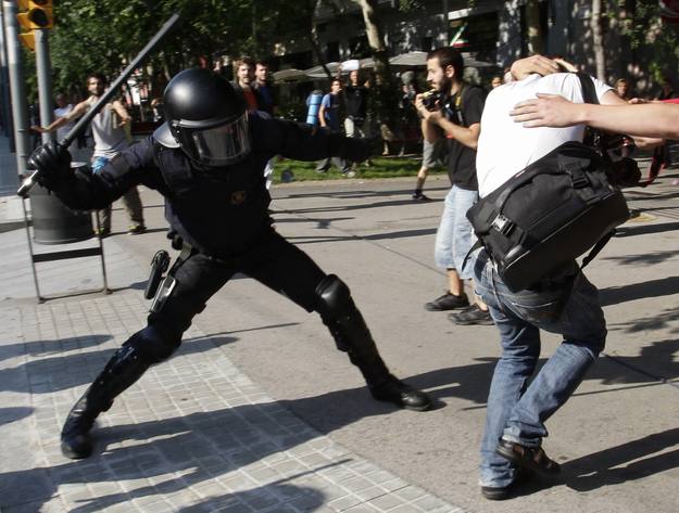 Uno de los antidisturbios golpea a un manifestante ante la puerta del Parlament