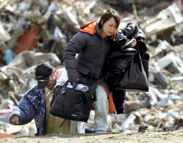 A woman carries her belongings away from her tsunami-stricken home in Rikuzentakata, Iwate Prefecture in northeastern Japan