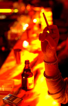 Una mujer fuma en un bar.