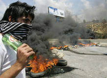 A pro-government loyalist stands by burning tyres and barricades on the main highway leading to southern Lebanon in Jiyeh area south of Beirut
