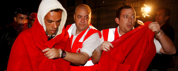 Uno de los 40 inmigrantes que navegaban en dos pateras y que han sido interceptadas por la Guardia Civil en aguas del Cabo de Gata, es ayudado por miembros de la Cruz Roja a su llegada al puerto de Almería.