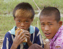 Boys eat bread which was given by a local donor at a village in Yangon